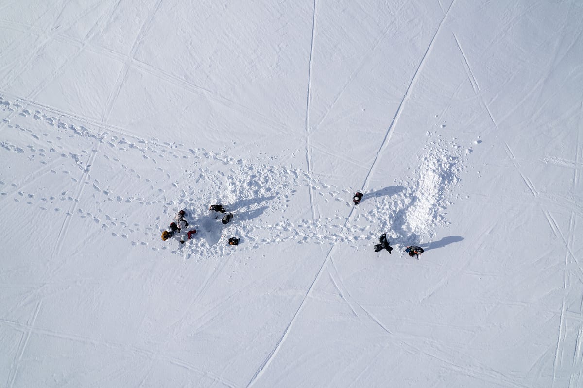 雪の斜面に集まった少人数のグループを上から見た様子